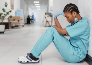 Sad female nurse sits on the hospital floor