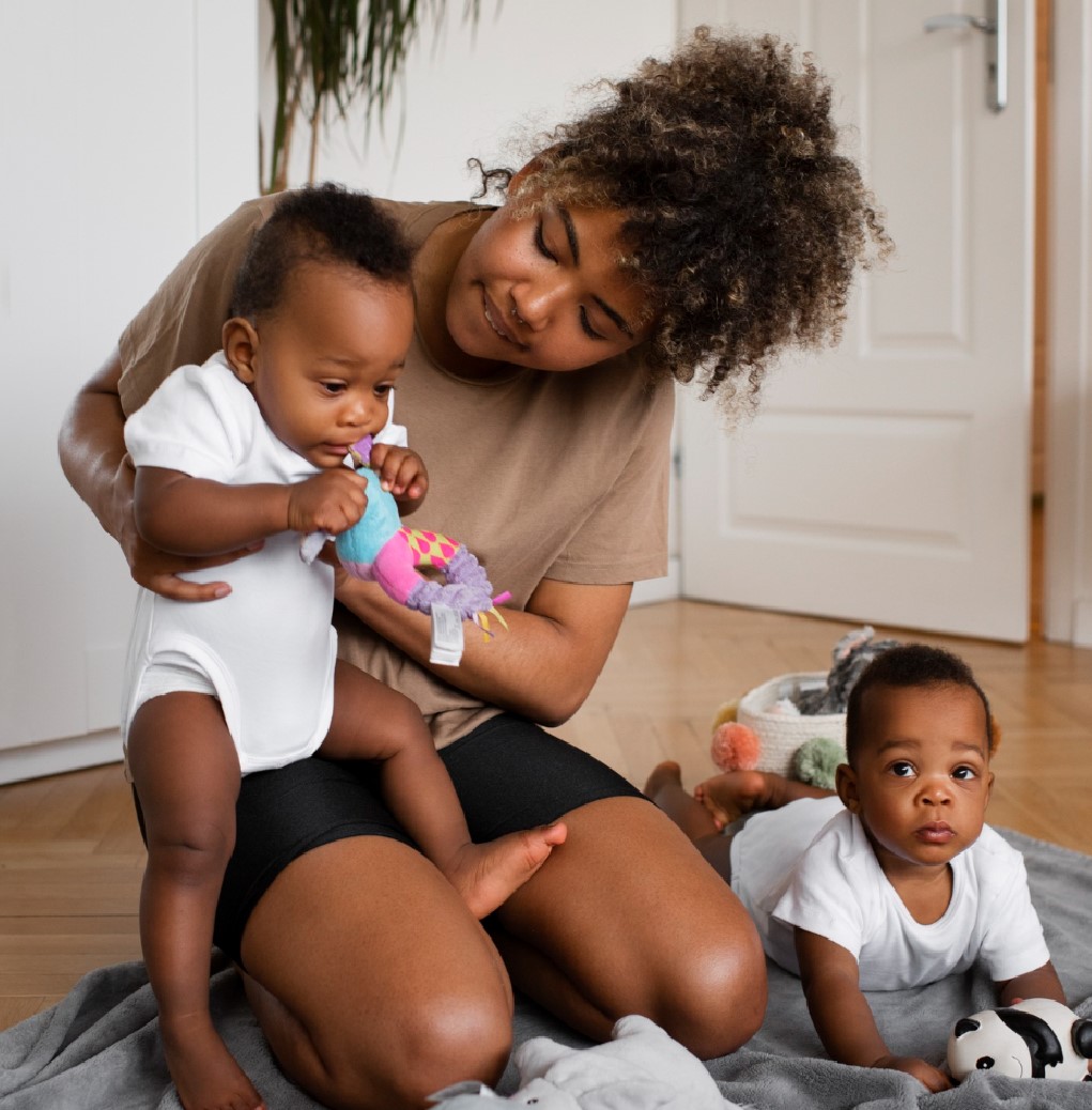 A woman and her two toddlers play together in a room illustrating fertility.